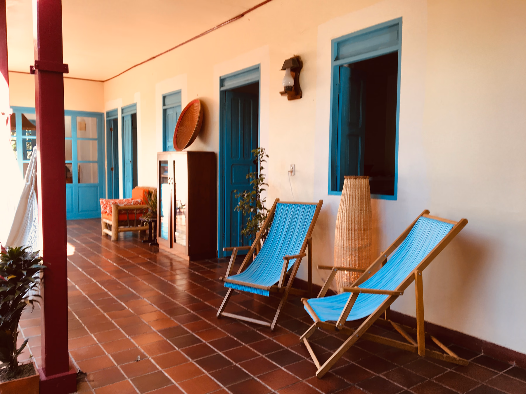 Corredor colonial con puertas azules y sillas para descansar