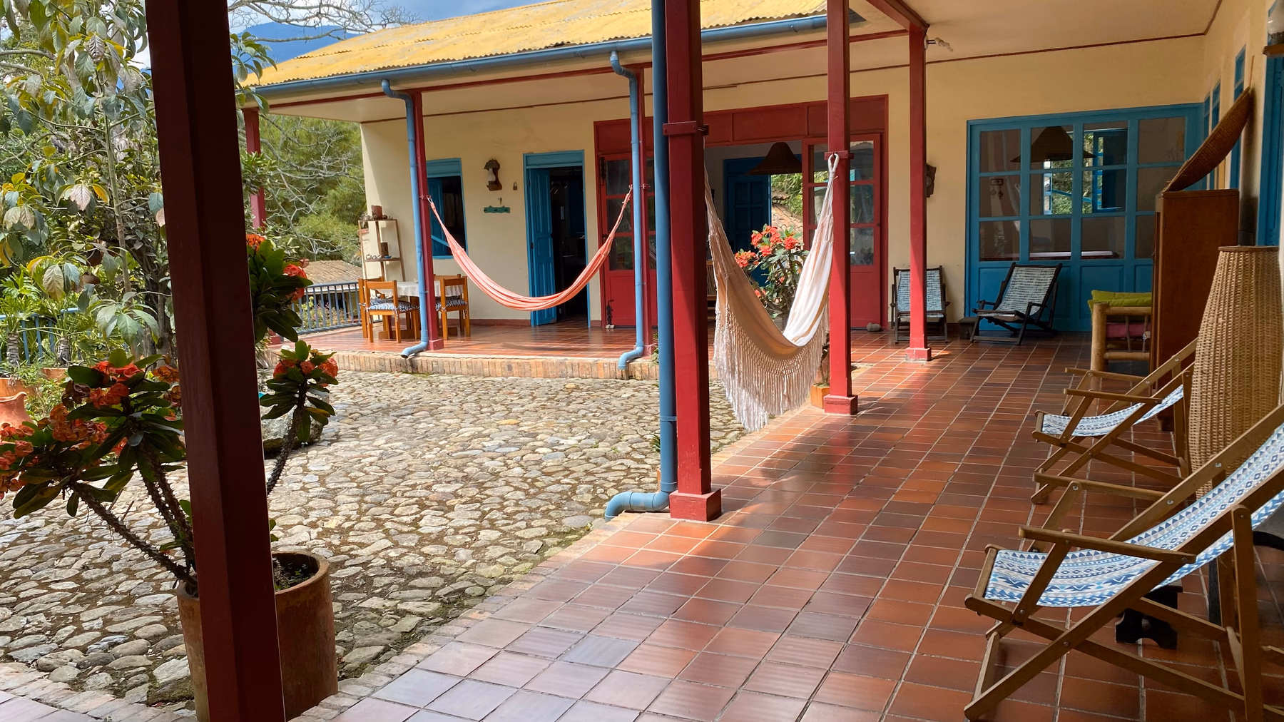 Patio central empedrado rodeado de corredores, plantas y hamacas